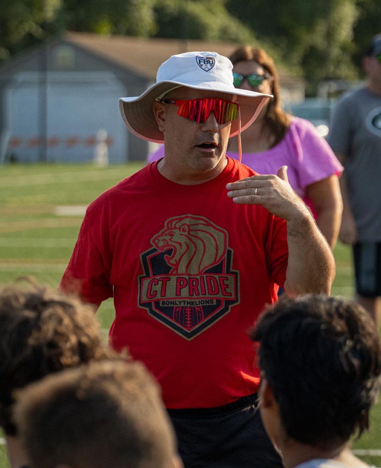 Coach Bouf speaking to his team during a football huddle